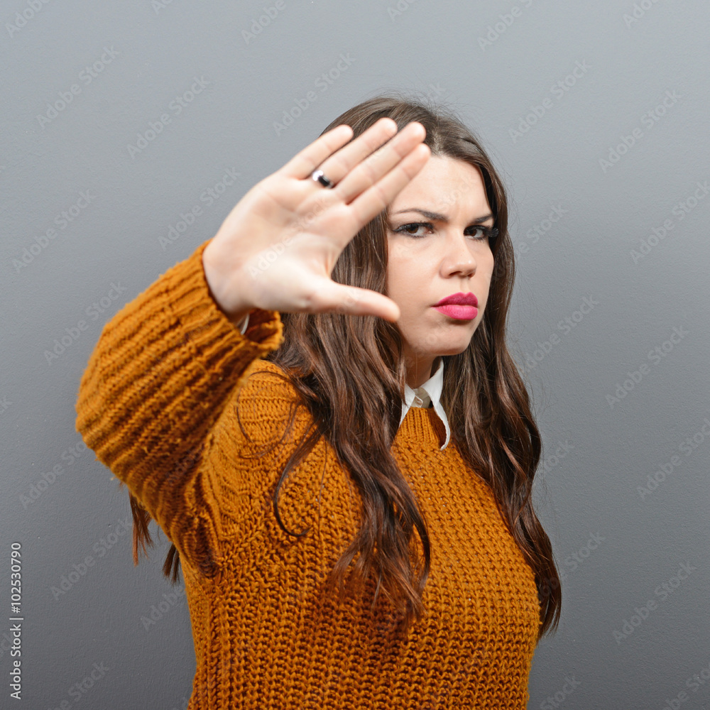 Portrait of woman showing stop with hand against gray background