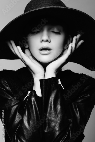 Portrait of a beautiful girl in a hat with eyes closed, posing in studio, black and white photography