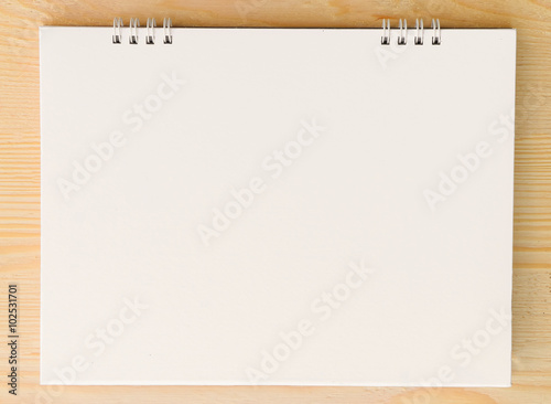 Blank paper sheet on bright wooden table.