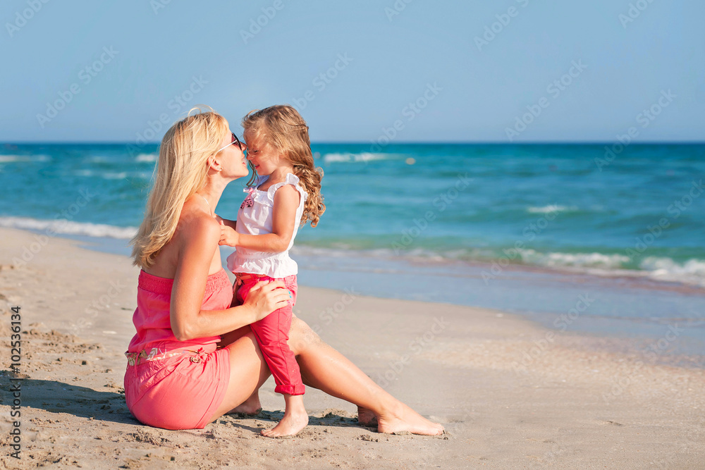 Young mother and her adorable daughter enjoying day at beach