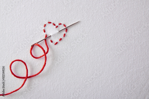 Slika na platnu Embroidered red heart on a white cloth top view