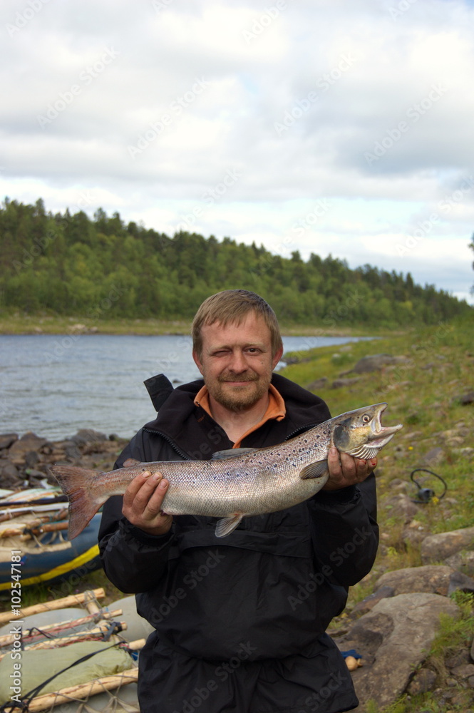 Fisherman holds his trophy salmon. Fishing on the Kola Peninsula, Russia. Fisherman holds his trophy salmon. Fishing on the Kola Peninsula, Russia.