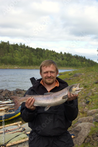 Fisherman holds his trophy salmon. Fishing on the Kola Peninsula, Russia.