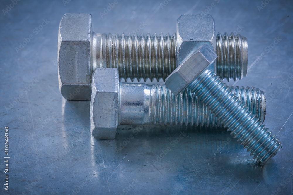 Steel screw-nuts with bolt on metallic background maintenance co Steel screw-nuts with bolt on metallic background maintenance co