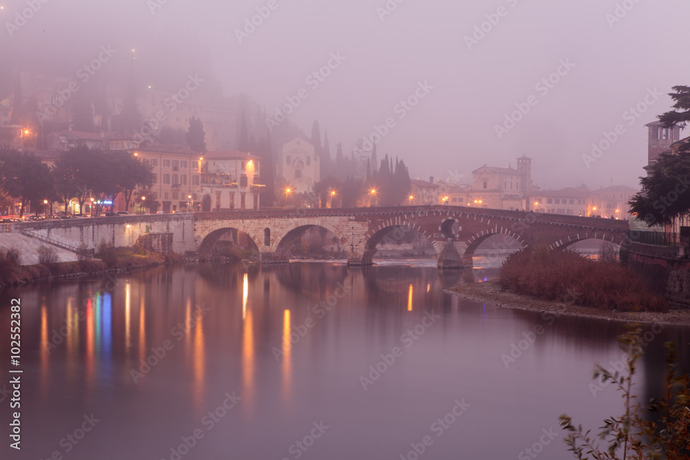 Ponte Pietra at a foggy evening. Verona - Italy.