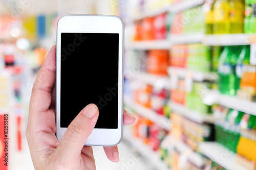 Hand holding smart phone over blur supermarket background
