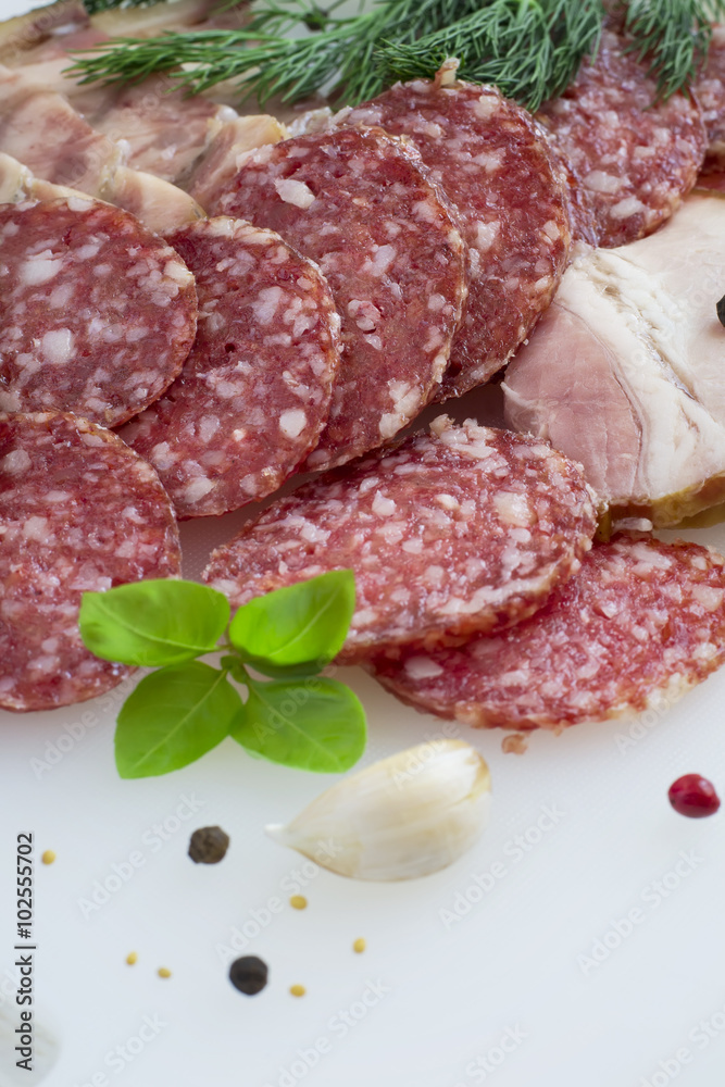 Slices of smoked sausage and spices on a white background Slices of smoked sausage and spices on a white background
