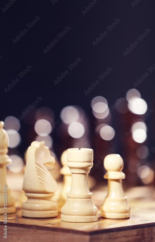 Chess pieces and game board on dark lights background