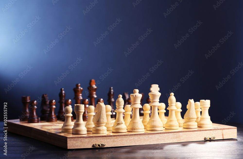 Chess pieces and game board on blue background