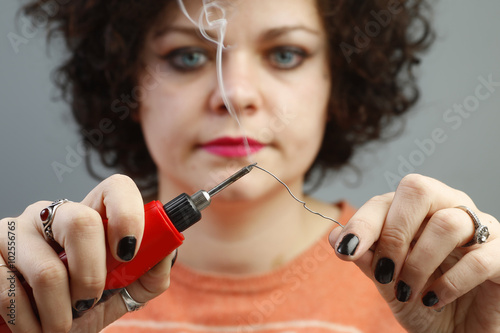 Φωτογραφία Attractive young woman melts bit of solder that makes smoke