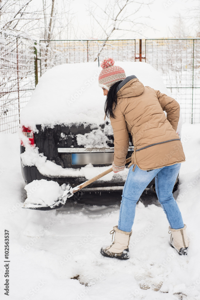 Woman cleaning snow around car Woman cleaning snow around car