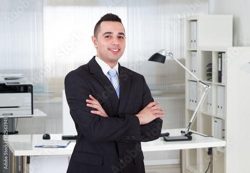 Young Businessman With Arms Crossed Standing In Office