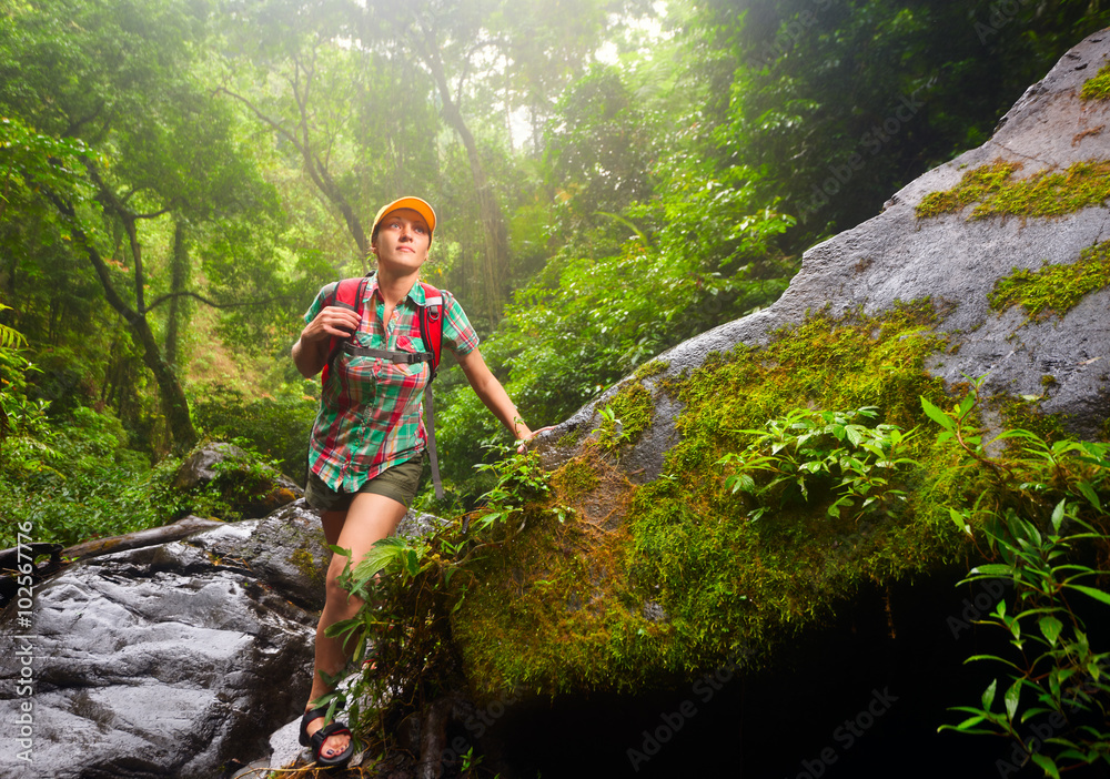 Woman tourist with a backpack walking along the trail in the rain forest.
