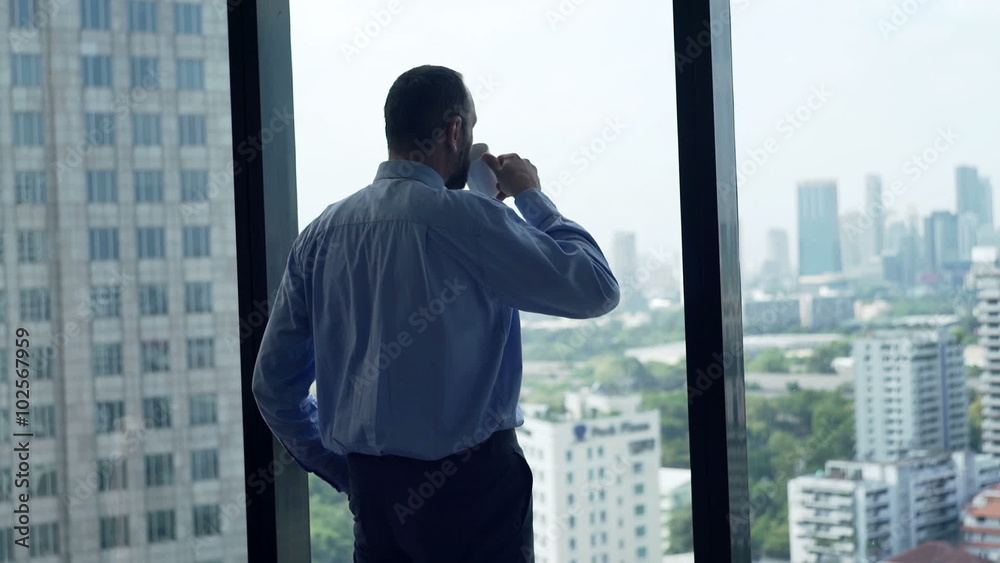 Young businessman drinking coffee and looking out of window
Young businessman drinking coffee and looking out of window