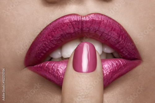 Pink lips and nail on mouth in close up photo