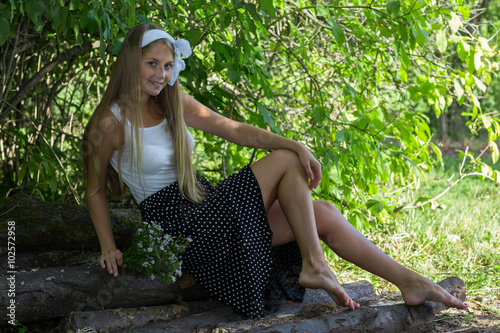 Young Caucasian woman sitting on wood and holding a bunch of flowers