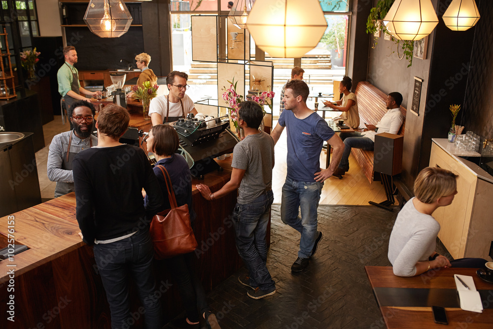 Customers at the counter of cafe being helped by barista