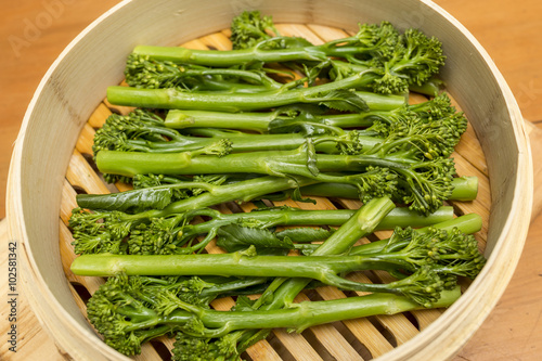 Close up of steamed broccoli in a bamboo pan.

