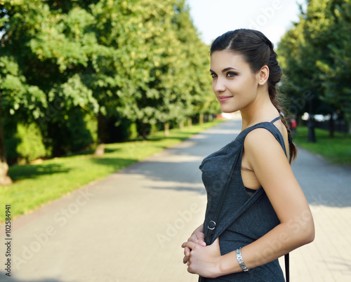 Young attractive cheerful woman walking in city park.