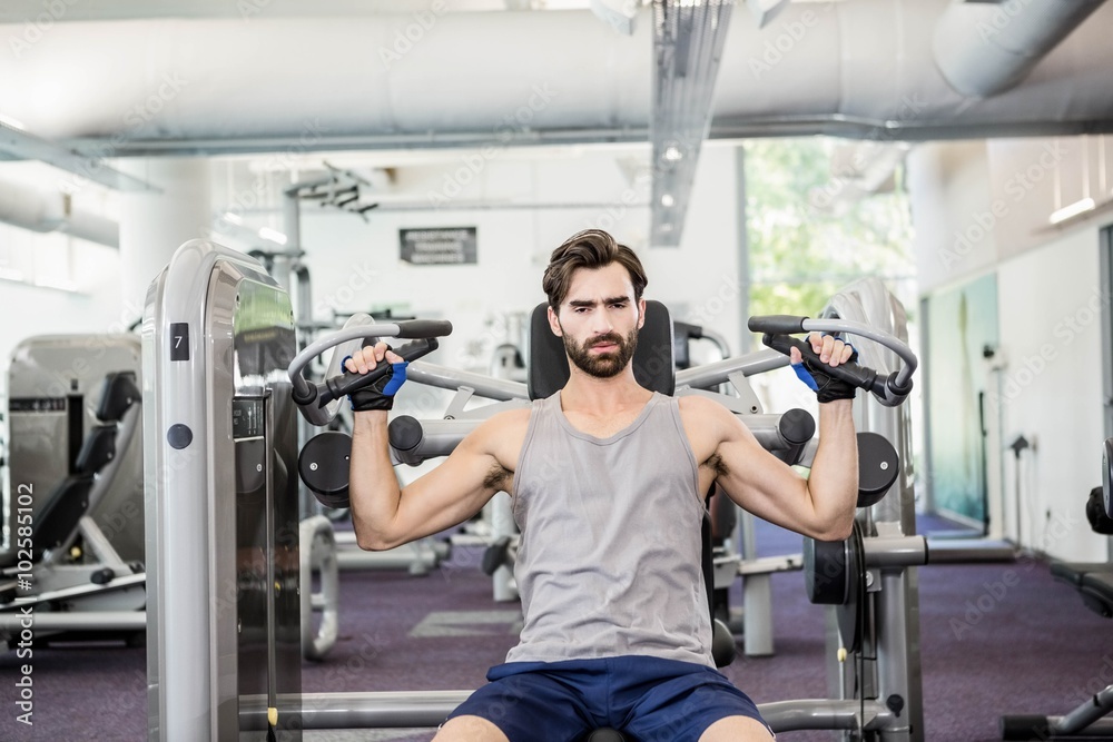 Focused man using weights machine for arms Focused man using weights machine for arms