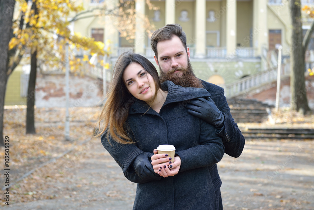 Fototapeta premium Fashion portrait of young couple drinking coffee in autumn park