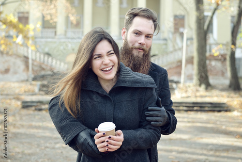Fashion portrait of young couple drinking coffee in autumn park © Khorzhevska