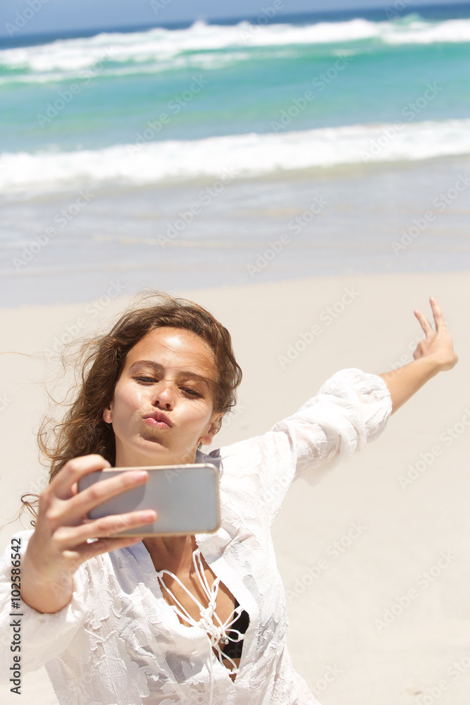 Young woman making funny face while taking selfie at the beach