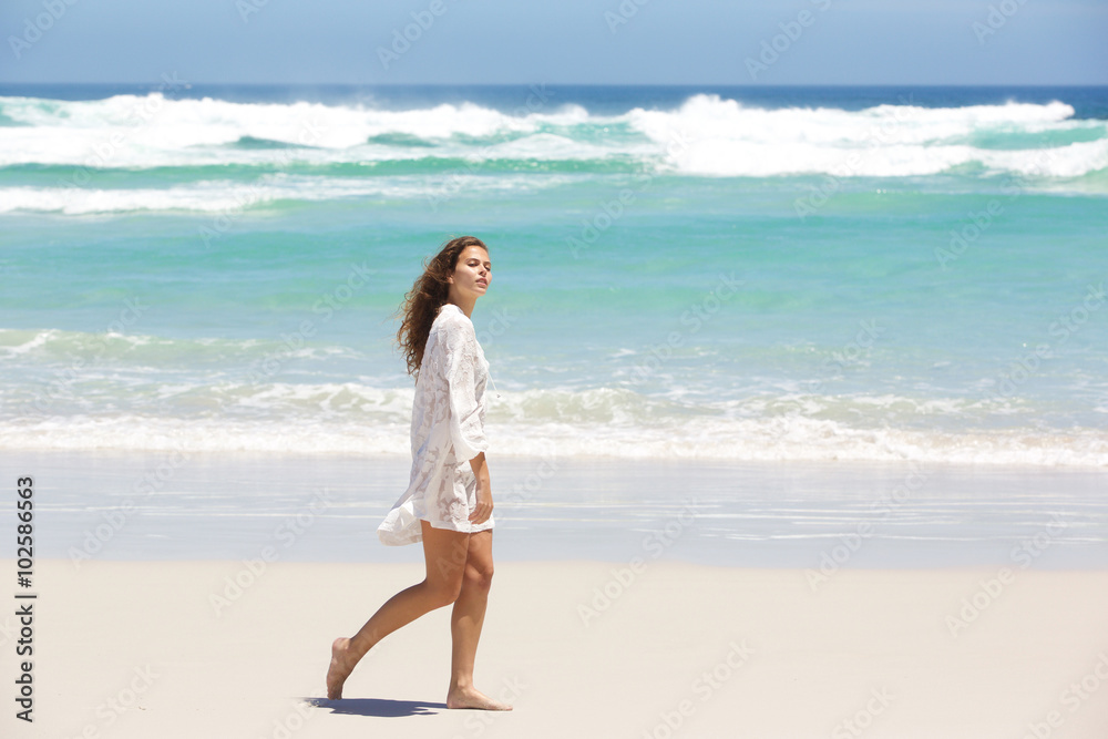 Young woman in summer dress walking on the beach Young woman in summer dress walking on the beach