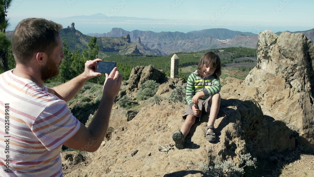 custom made wallpaper toronto digitalFather doing photo of his son on smartphone in the mountains
