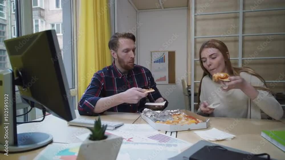 Man and woman eating pizza at workplace. Man and woman eating pizza at workplace.