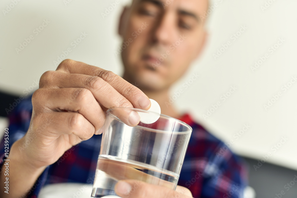 man putting an effervescent tablet into a glass with water man putting an effervescent tablet into a glass with water