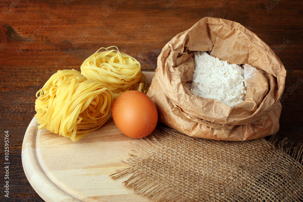 pasta with eggs and flour on wooden cutting Board on white wooden table pasta with eggs and flour on wooden cutting Board on white wooden table
