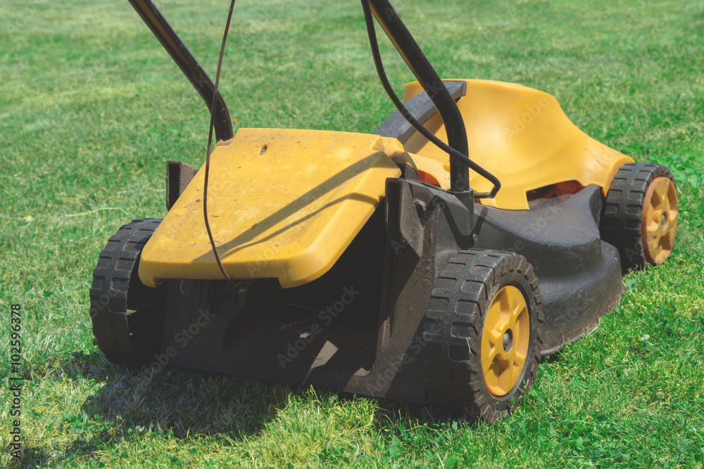 Fototapeta premium Lawn mover on a green grass field.