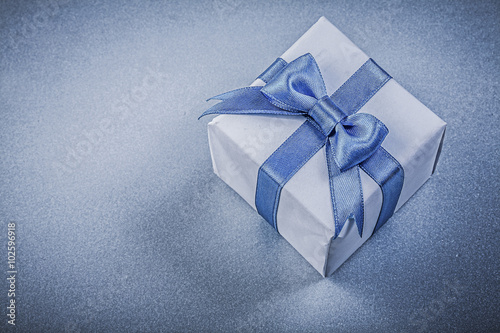 Present box with bow on blue background