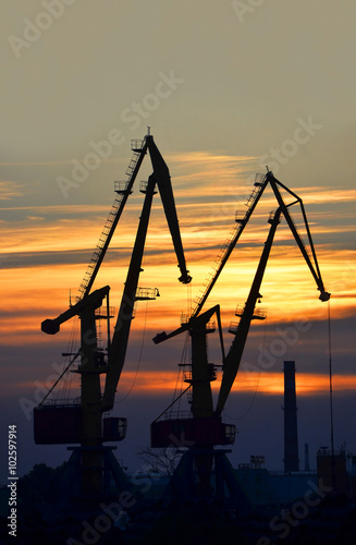 Port cargo crane over sunset sky background