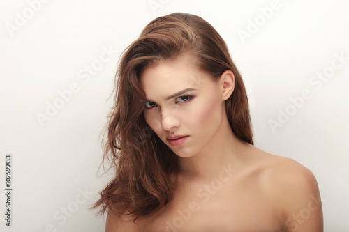 Closeup portrait of young cute laughing brunette woman in black bra with adorable makeup posing bare shoulders on white studio background