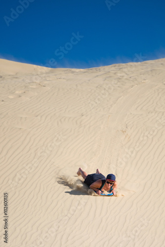 Excited Woman sandboarding on Te Paki sand dunes, New Zealand © ventura