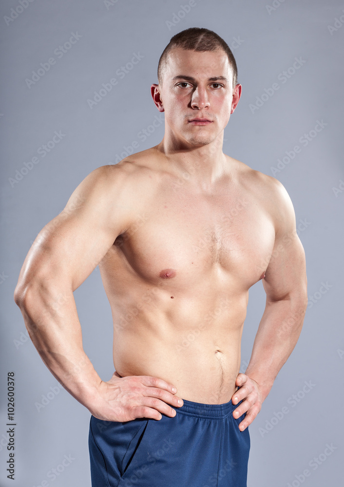 muscular young topless man on gray background