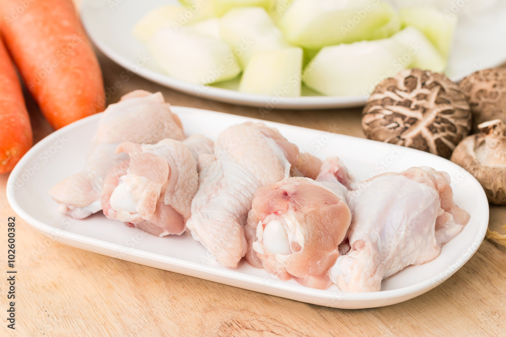 Raw chicken legs with fresh vegetable on wooden.