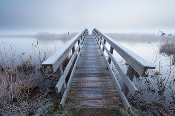 Fototapete Landschaften Holzbrücke über Fluss im Winter  © Olha Rohulya