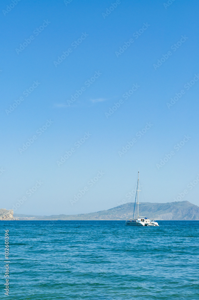 View of the Black Sea bay and moored yacht in village of Novyi Svit (New World) in summer, Crimea, Ukraine