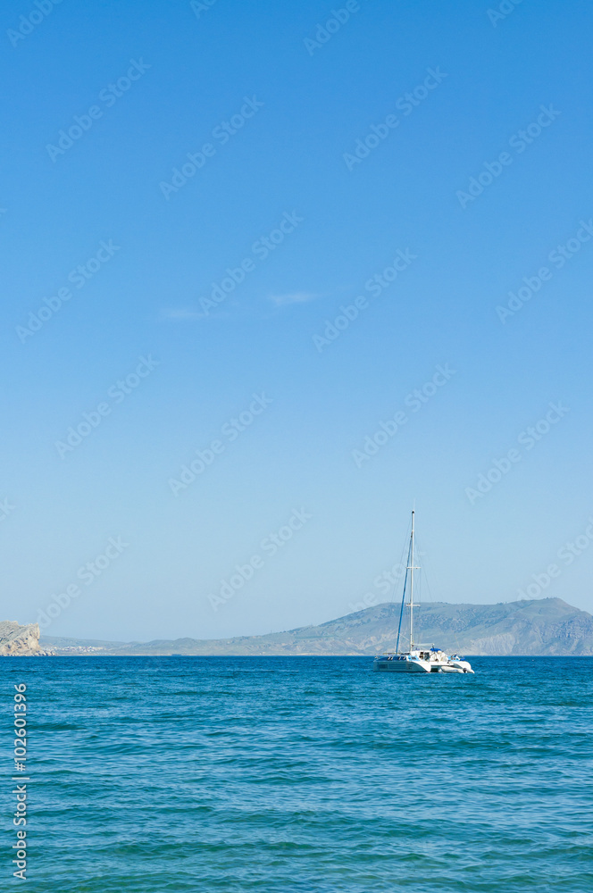 Fototapeta premium View of the Black Sea bay and moored yacht in village of Novyi Svit (New World) in summer, Crimea, Ukraine