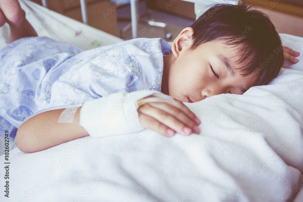 Asian boy sleeping on sickbed, saline intravenous (IV) on hand. Asian boy sleeping on sickbed, saline intravenous (IV) on hand.