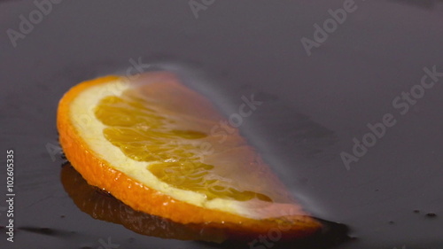 Close-up of a delicious orange slice falling into chocolate syrup