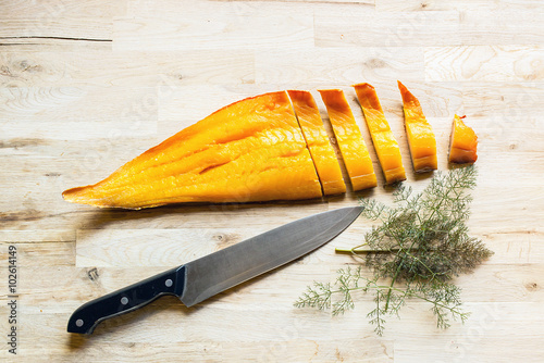 Canvastavla beautiful yellow smoked haddock fish fillet and slices with a kitchen knife and