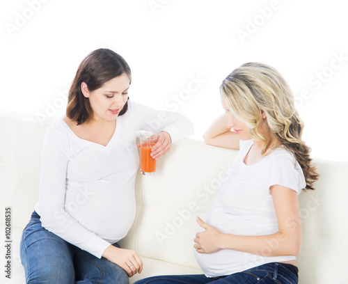 Two young beautiful pregnant women on a sofa