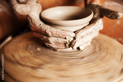 Hands of a woman creating a clay jar on a potter's wheel