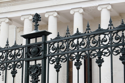 Metal decorative fence. / Decorative metal fence on the background of the colonnade of the facade of the building.