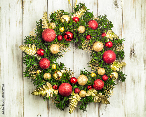 Christmas wreath with baubles on wooden background.