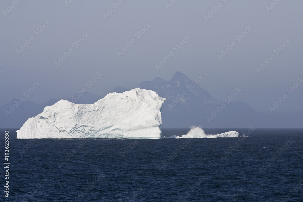 Iceberg Floating in Ocean with Mountains in the Background